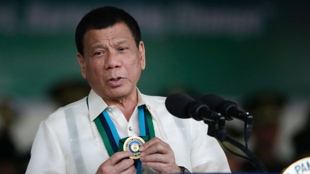 Philippine President Rodrigo Duterte shows a medal during his speech to troops in Quezon City in December.