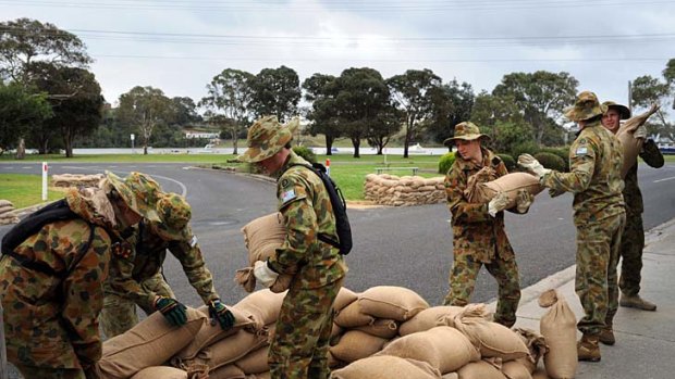 Members of the armed forces lay sandbags in Barkes Avenue, Lakes Entrance.