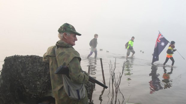 Protesters wade through the swamp at Dowds Morass, near Sale, as duck hunter Geoff Fisher looks on.