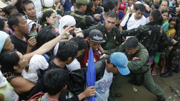 Typhoon survivors jostle to get a chance to board a C-130 military transport plane in the Philippines.