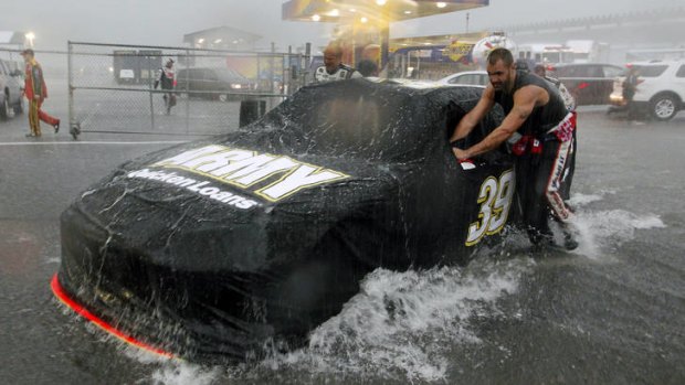 Crew members push a car in the downpour.
