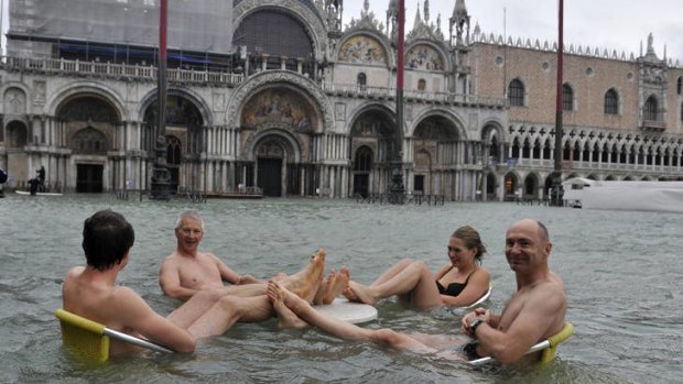 Unexpected lagoon ... tourists make the best of the rising water in St Mark's Square.