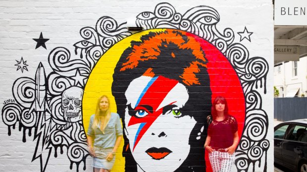 Artist Sofia Fitzpatrick and Blender Gallery owner, Tali Udovich, with a mural of David Bowie on the gallery's wall.
