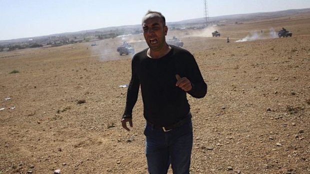 A man runs from tear gas fired by Turkish armed forces on the Turkish side of the border with Syria.