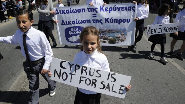 Students hold placards, including one that reads in Greek "we don't sell out "during a parade for Greek independence day at the southern port city of Limassol, Cyprus.