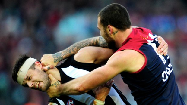 Demon Mitch Clark comes to grips with Collingwood defender Nathan Brown.