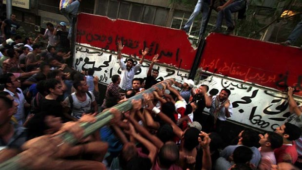 Egyptian demonstrators demolish a concrete wall, built to protect the Israeli embassy in Cairo, before storming the building.