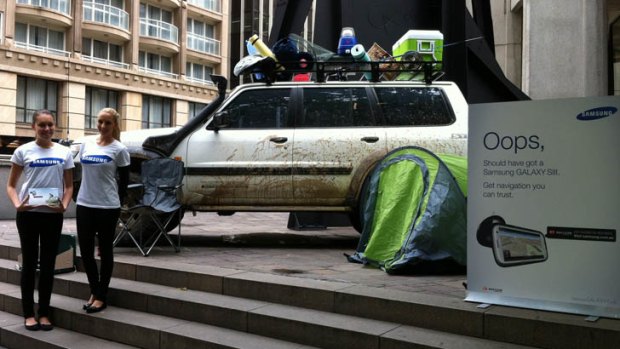 A muddied up 4WD with a sign that appears to mock Apple Maps at Australia Square in Sydney.