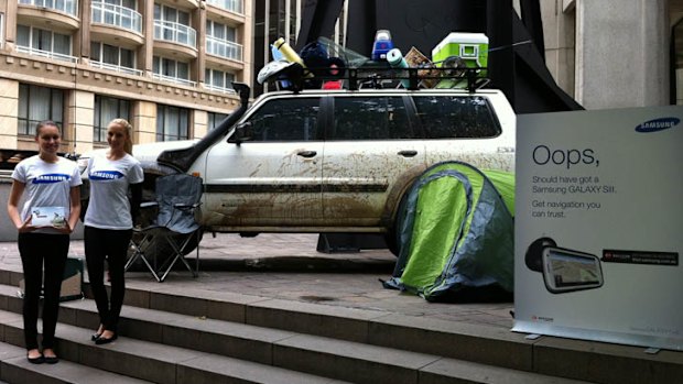 A muddied up 4WD with a sign that appears to mock Apple Maps at Australia Square in Sydney.