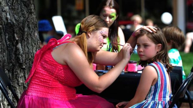 Madelyn Terata, 7, of Kingston, has her face painted by Natalie Porter, of Mawson, at Green Square, Kingston.