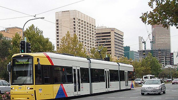 A tram runs between the two lanes of cars in Adelaide.