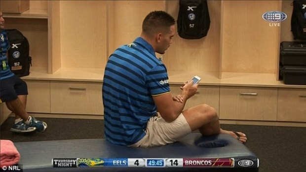 Corey Norman uses his mobile phone in the dressing room while the game is still live.