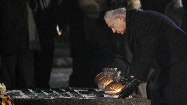In memoriam ...  Benjamin Netanyahu places a candle at a memorial to the Holocaust.
