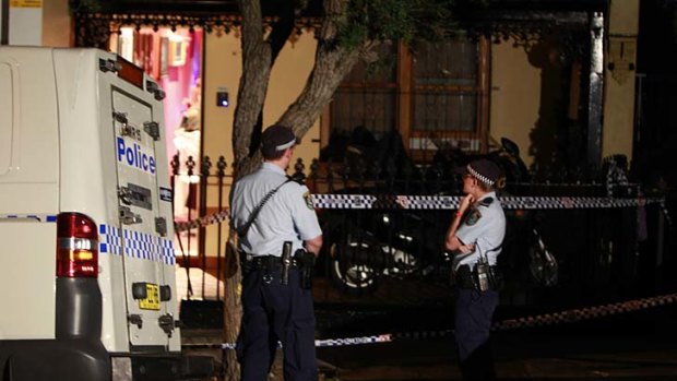 Police stand guard after three people were shot at this home in Petersham.