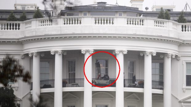 Law enforcement officers examine a window of the White House that was hit by a bullet.