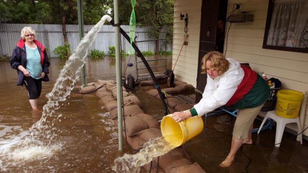 Fighting ... Lyn Currie with her daughter Lau try to keep floodwater at bay at their home at Tallygaroopna yesterday.