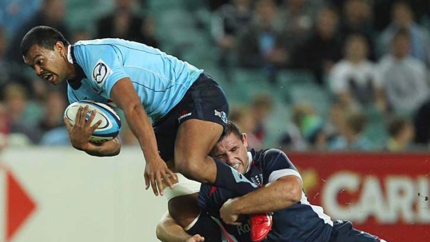 Breaking through: Kurtley Beale tries to force his way through a tackle in last night's win over the Melbourne Rebels.