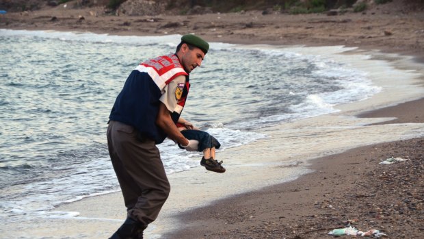 A paramilitary police officer carries the lifeless body of a  migrant child after a number of migrants died and a smaller number  were reported missing after boats carrying them to the Greek island of Kos capsized, near the Turkish resort of Bodrum early Wednesday, Sept. 2, 2015. (AP Photo/DHA) TURKEY OUT