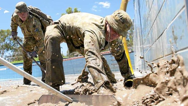 Soldiers help pump mud following the Mitchell floods in 2012.