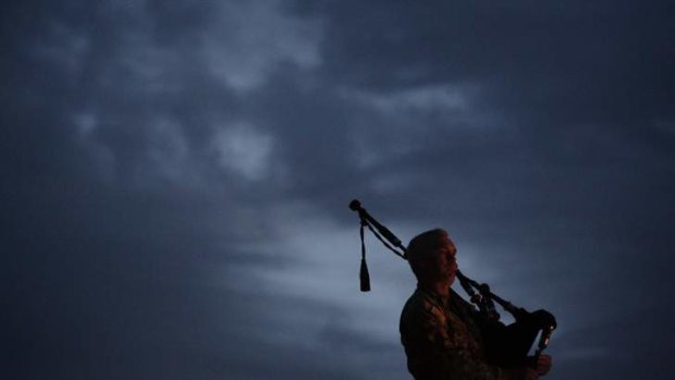 As the sun rises: A bagpipe player at Tarin Kowt base's dawn service.