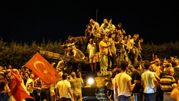 People gather on a Turkish army tank at Ataturk Airport in Istanbul.