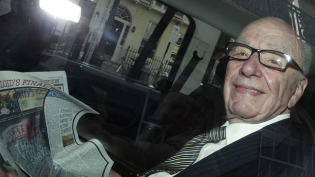 All smiles ... Rupert Murdoch holds a copy of <em>The Sun</em> as he is driven away from his flat earlier this week.