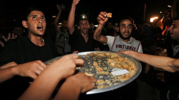 Palestinians celebrate with sweets outside the Shifa hospital in Gaza City following the reported capture of an Israeli soldier during fighting in the Gaza Strip.