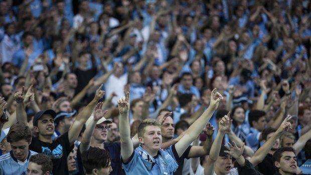 Singing in the rain: Sydney FC fans get behind their side in the derby.