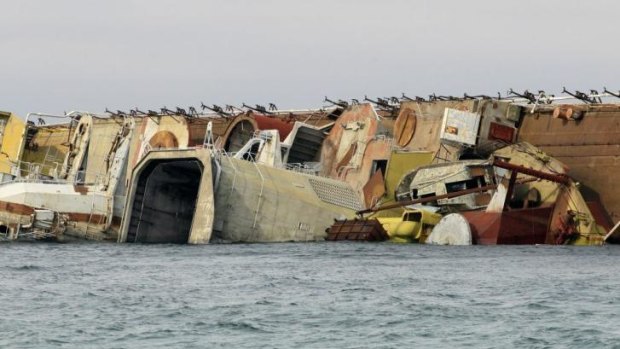 The decommissioned Russian anti-submarine vessel Ochakov lies on its side off the Black Sea shore, where it was sunk to block Ukrainian naval vessels from entering the sea from their base.