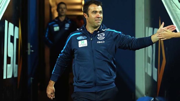 An obviously happy Chris Scott high-fives a fan as he walks out of the change rooms.