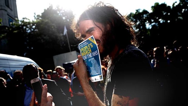 Comedian Russell Brand holds a flyer for a pro-NHS demonstration as he speaks to a members of a crowd that gathered in Parliament Square to protest, on June 21, 2014 in London, England.