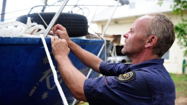 A volunteer Coastguard member helps tie down a boat in Port Douglas before Tropical Cyclone Ita made landfall.