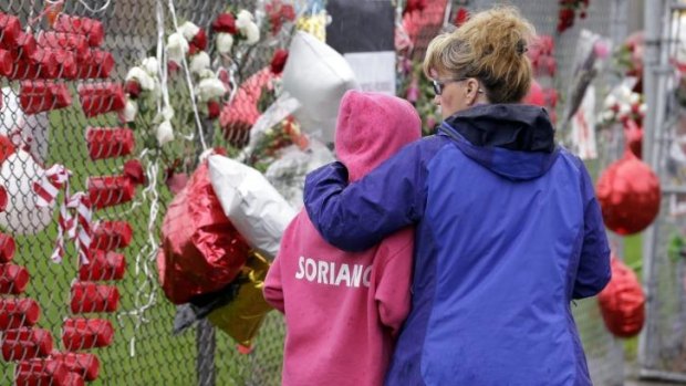 Gabby Soriano, 11, is embraced by her mother, Gay, as the visit a memorial to the school shooting victims. Gabby's cousin, Gia, was among those killed.