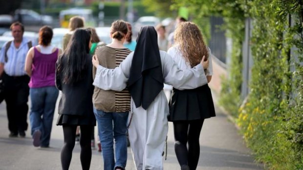 A nun comforts students after the stabbing death of one of their teachers.