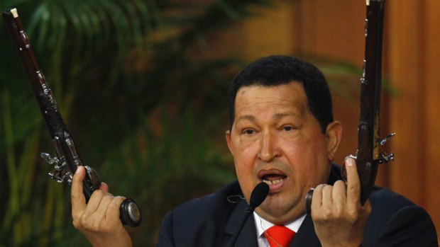 Venezuela's President Hugo Chavez shows the pistols of independence hero Simon Bolivar during a ceremony to mark the his birthday in Caracas on July 24, 2012.