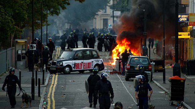 Riot police tackle a mob after a number of cars are set alight in London on August 8, 2011.