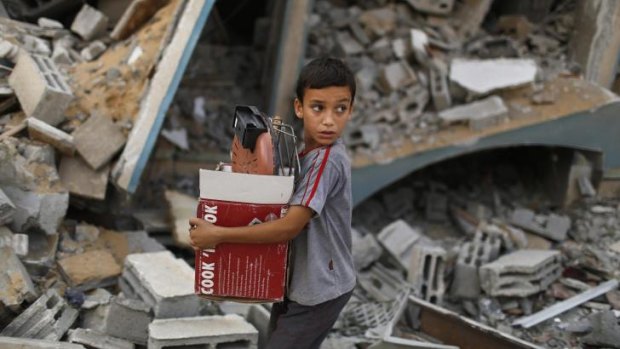 A Palestinian boy carries belongings past a destroyed house in Gaza's Shujaiya neighbourhood.