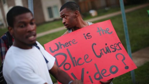 Demonstrators protest next to the spot where 18-year-old Michael Brown was shot by police on Saturday in Ferguson, Missouri. Police responded with tear gas and rubber bullets.