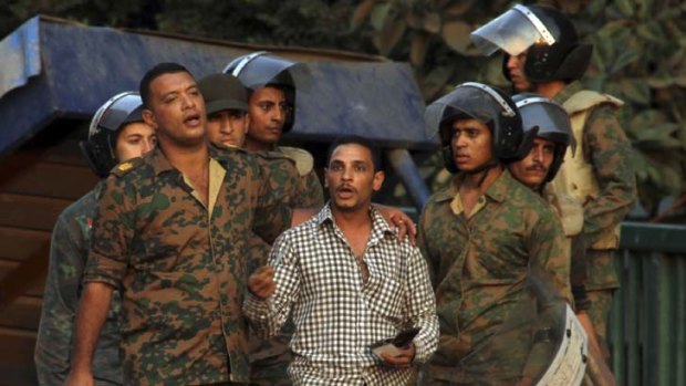 Night of violence: Egyptian soldiers detain a protester outside the Israeli embassy in Cairo.