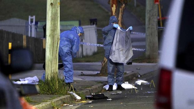 Police forensic officers examine the evidence after the triple shooting.