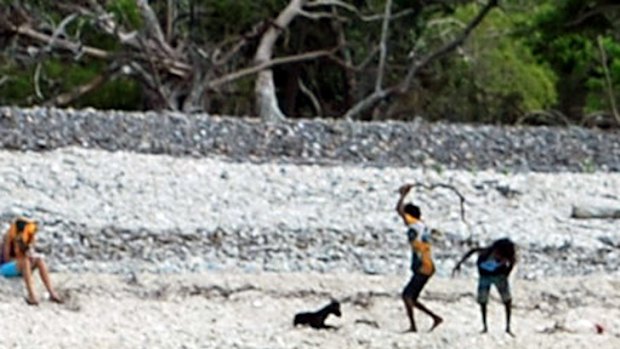 One of the children begins to hit the goat on Palm Island.