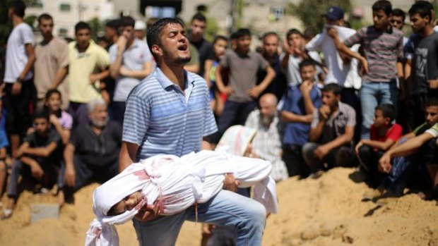 A man at a funeral in Beit Lahiya carries the body of a girl from the Abu Nejim family, whom medics said was killed along with eight other family members by an Israeli air strike.