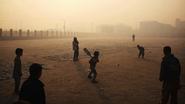 Pitched battle: Boys play cricket on a hazy winter's morning in Kabul.