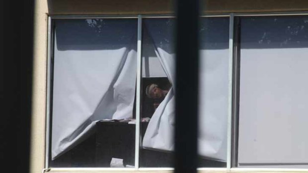 The alleged hostage taker looks through the window.