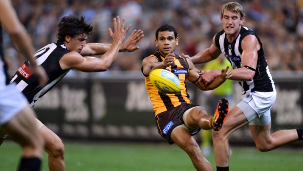 Hawthorn's Cyril Rioli gets a kick away despite heavy pressure from Collingwood players at the MCG.