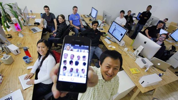 Color co-founder Bill Nguyen holds up his Apple iPhone with photos of himself using the Color application as he poses with staff members at the company's offices in Palo Alto, California.