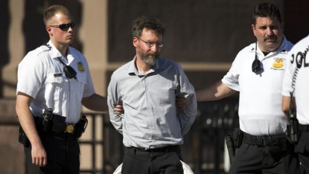 A man, identified as Mathew Evan Goldstein, is led away in handcuffs by uniformed Secret Service police officers.