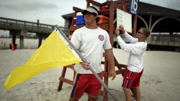 Tybee Island Ocean Rescue Senior Lifeguard Todd Horne, right, and Mark Eichenlaub, left, prepare to hang a yellow flag that warns swimmers of strong rip currents from Hurricane Arthur along the beach on Tybee Island, Georgia.