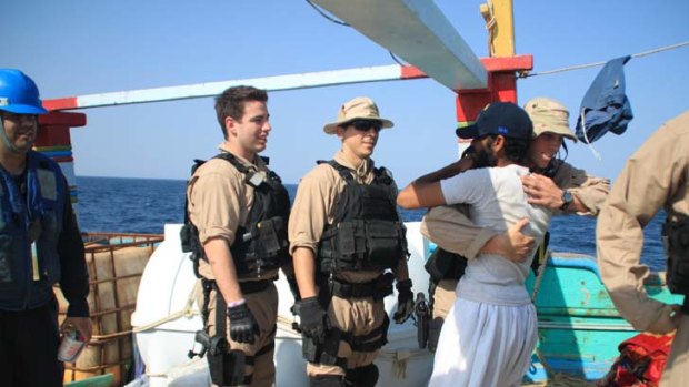 An American sailor greets a crew member of the Iranian-flagged dhow Al Molai after rescuing the fishing vessel from pirates in the Arabian Sea.