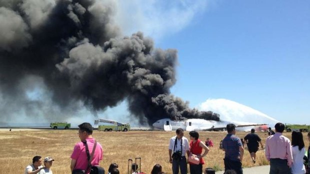 Evacuated passengers are seen on the tarmac as Asiana Airlines flight 214 burns on the runaway. Reports suggest not all were graceful under the great pressure of the evacuation.